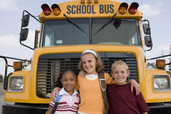 Three students in front of bus